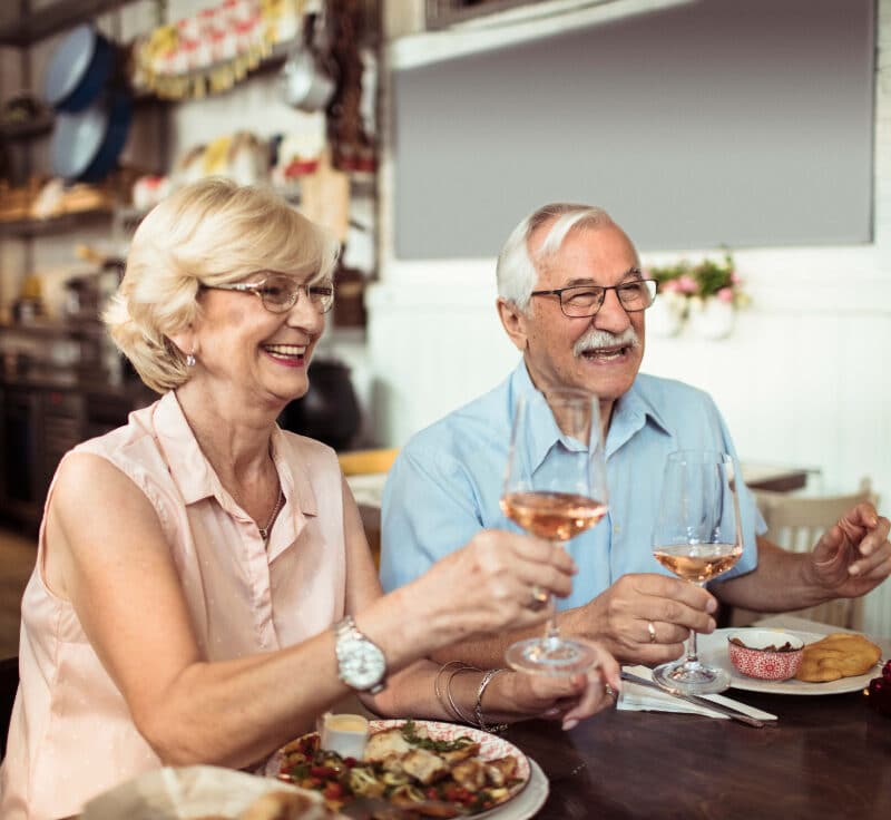 A senior couple enjoying a meal and a glass of wine.