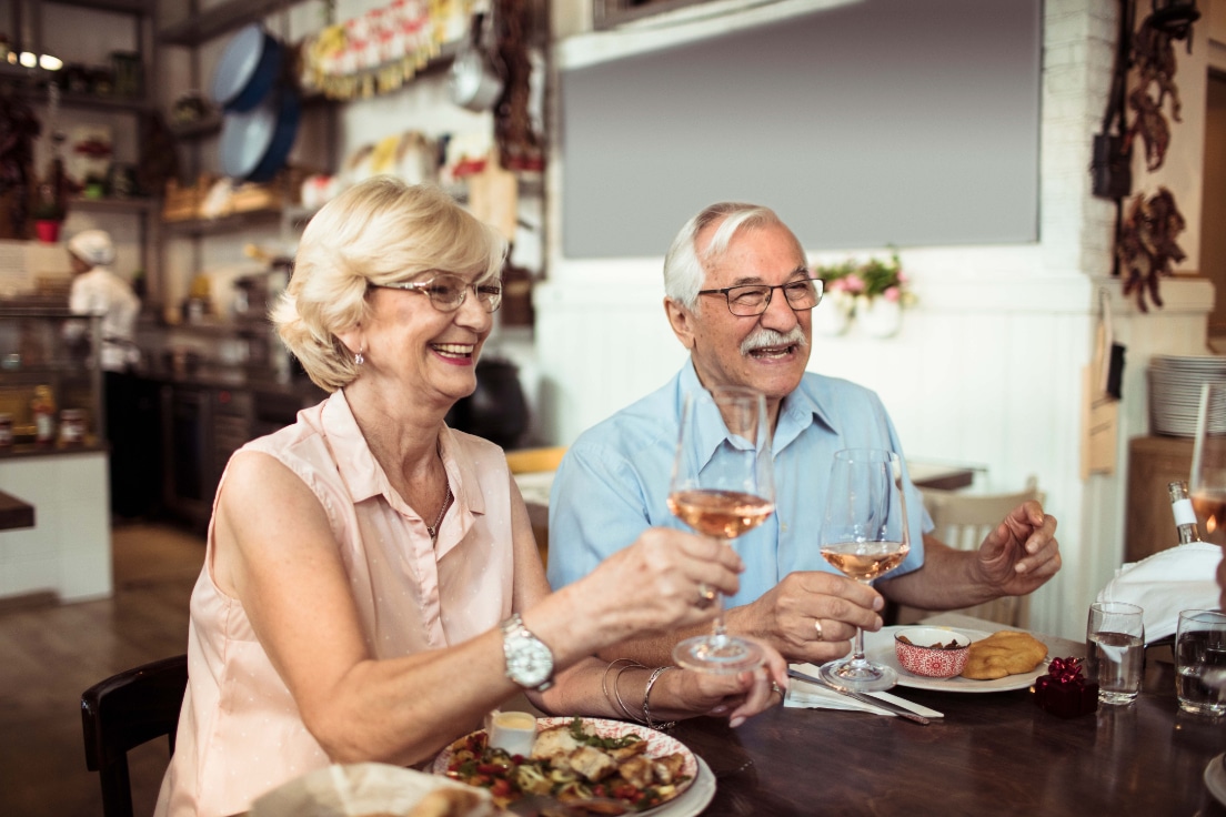 A senior couple enjoying a meal and a glass of wine.